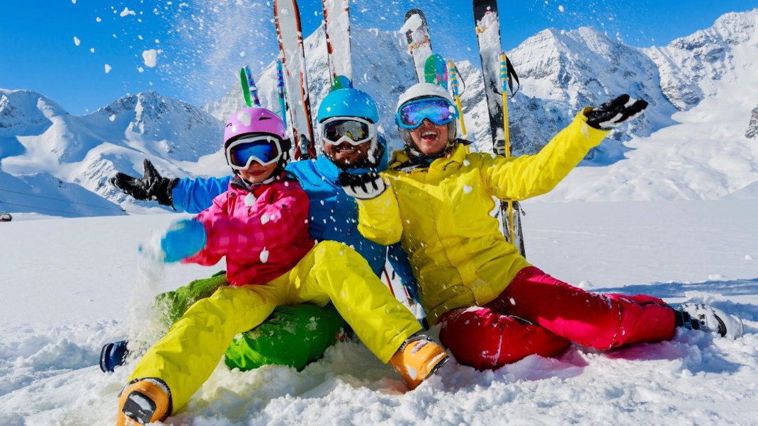 A group of people sitting in the snow with skis.